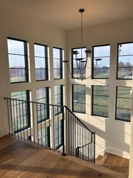 stairs featuring hardwood / wood-style floors, a notable chandelier, and a healthy amount of sunlight