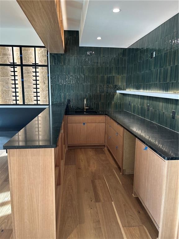 kitchen with tasteful backsplash, light brown cabinetry, sink, and light hardwood / wood-style floors