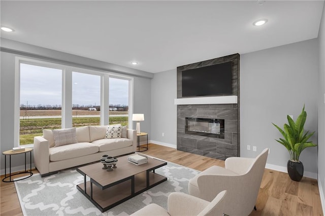 living room featuring a tile fireplace, a wealth of natural light, and light hardwood / wood-style flooring