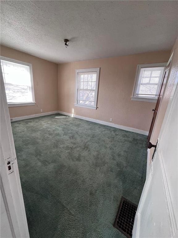 carpeted empty room featuring a textured ceiling