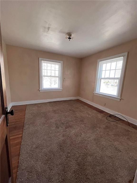 unfurnished room with dark carpet and a healthy amount of sunlight