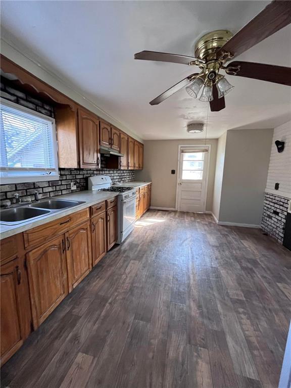 kitchen with backsplash, ceiling fan, dark wood-type flooring, white range with gas stovetop, and sink