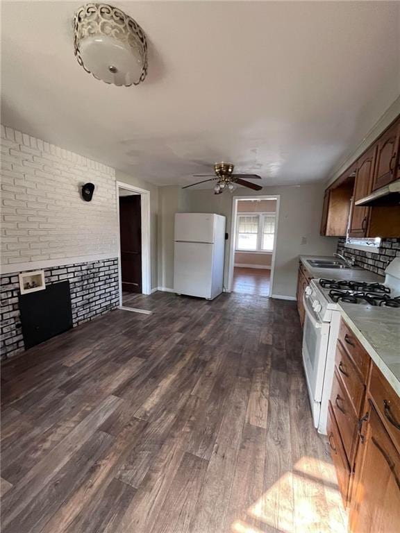 kitchen featuring dark hardwood / wood-style flooring, brick wall, ceiling fan, white appliances, and sink