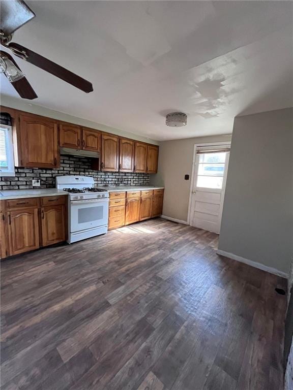 kitchen with backsplash, dark hardwood / wood-style floors, white gas range oven, and ceiling fan