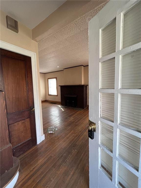 unfurnished living room with a textured ceiling and dark wood-type flooring