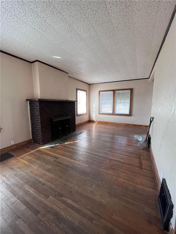 unfurnished living room with ornamental molding, dark wood-type flooring, and a brick fireplace