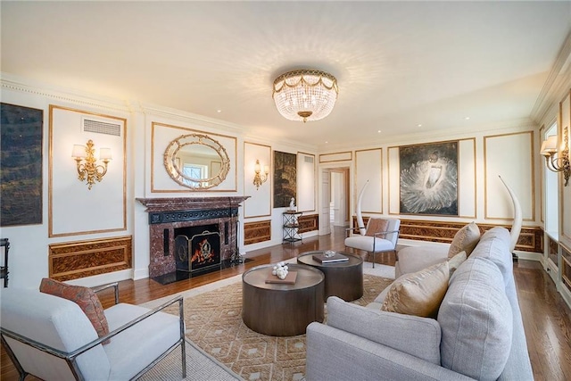 living room with an inviting chandelier, hardwood / wood-style flooring, a fireplace, and ornamental molding