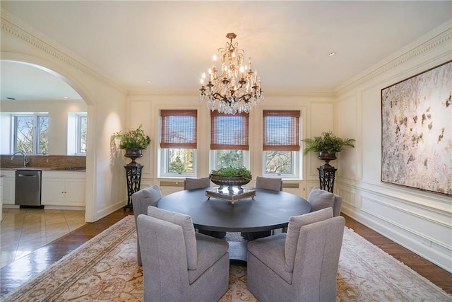 dining area featuring light wood-type flooring, a healthy amount of sunlight, crown molding, and an inviting chandelier