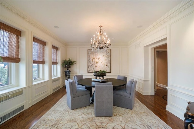 dining room with wood-type flooring, ornamental molding, a notable chandelier, and radiator