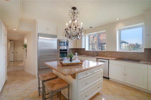 kitchen with built in appliances, backsplash, white cabinetry, and a center island