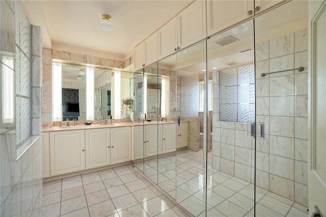 bathroom with tile patterned flooring, a shower with shower door, vanity, and tile walls