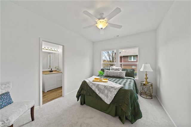 carpeted bedroom with ensuite bathroom, ceiling fan, and sink