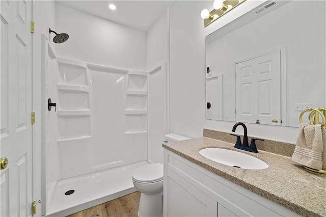 bathroom with hardwood / wood-style floors, vanity, toilet, and walk in shower