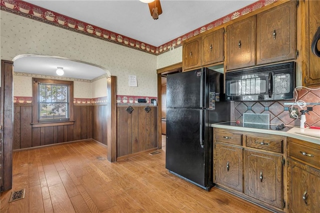 kitchen with black appliances, ceiling fan, light hardwood / wood-style flooring, and tasteful backsplash