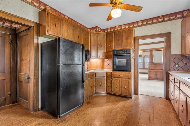 kitchen with light hardwood / wood-style flooring, black appliances, backsplash, and ceiling fan