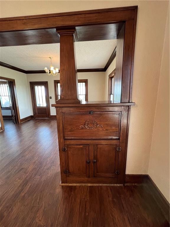 room details with a textured ceiling, an inviting chandelier, wood-type flooring, decorative columns, and ornamental molding