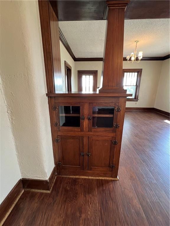 details featuring a textured ceiling, hardwood / wood-style floors, a notable chandelier, ornate columns, and ornamental molding