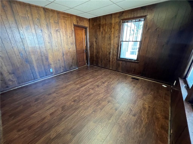 spare room with dark wood-type flooring and wood walls