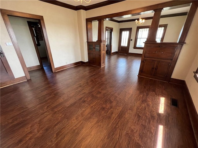 foyer with dark hardwood / wood-style flooring, decorative columns, an inviting chandelier, and crown molding