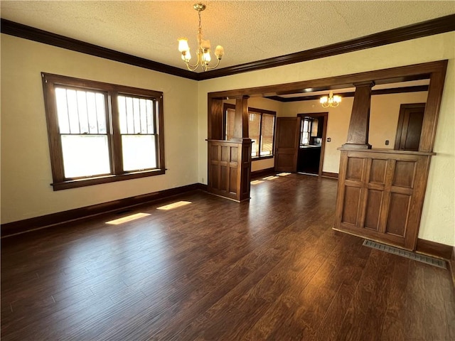 unfurnished living room featuring a textured ceiling, an inviting chandelier, decorative columns, dark wood-type flooring, and ornamental molding