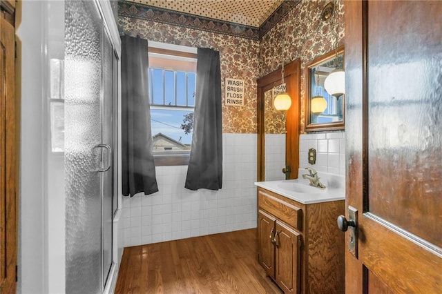 bathroom featuring tile walls, a shower with door, hardwood / wood-style flooring, and vanity