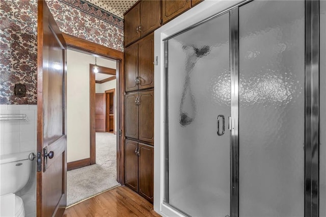 bathroom with hardwood / wood-style floors, toilet, and an enclosed shower