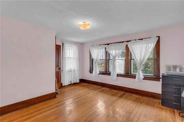 empty room with light hardwood / wood-style floors and a textured ceiling