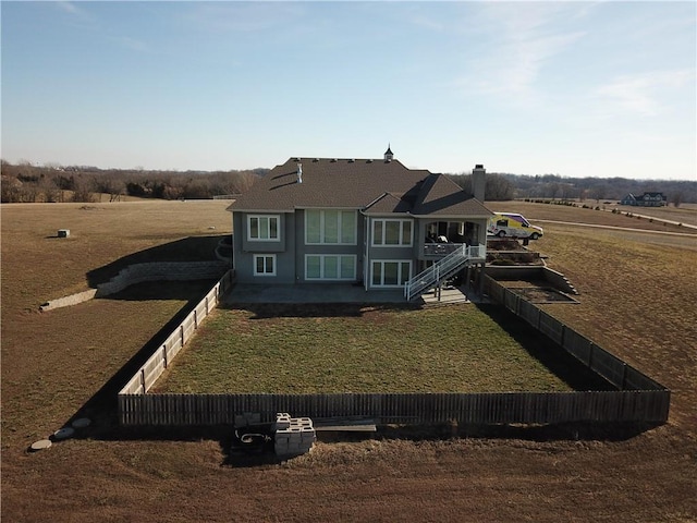 view of front of house with a rural view and a front lawn