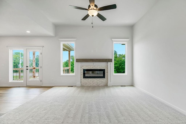 unfurnished living room with ceiling fan, light colored carpet, french doors, and a brick fireplace