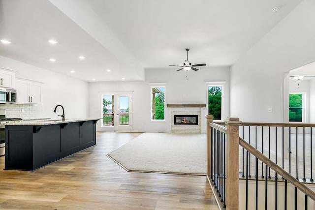 kitchen featuring light hardwood / wood-style flooring, decorative backsplash, stove, a breakfast bar area, and ceiling fan