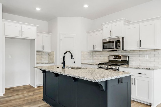 kitchen with sink, stainless steel appliances, light wood-type flooring, and backsplash