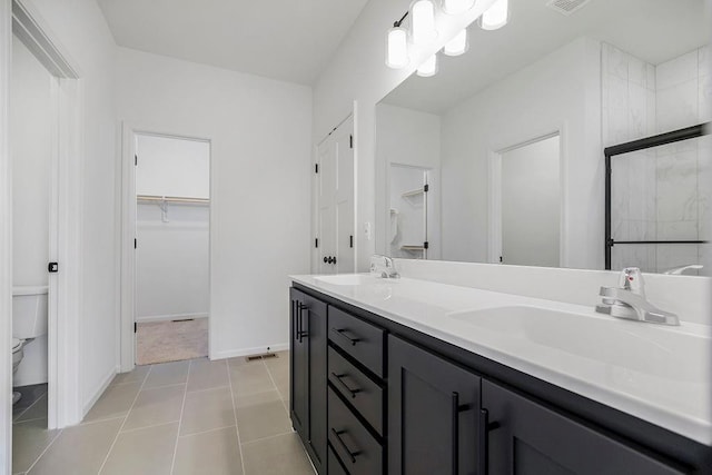 bathroom with tile patterned flooring, toilet, vanity, and tiled shower