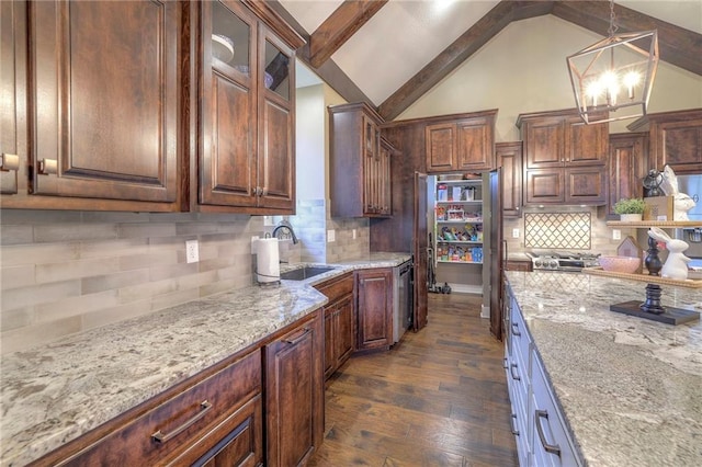 kitchen with sink, dark hardwood / wood-style flooring, hanging light fixtures, light stone countertops, and dark brown cabinets