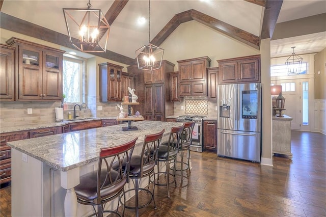 kitchen with decorative backsplash, appliances with stainless steel finishes, dark hardwood / wood-style flooring, decorative light fixtures, and a center island