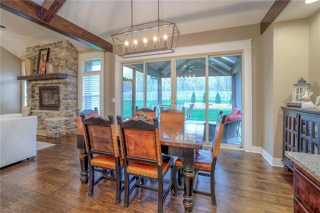 dining room featuring dark hardwood / wood-style flooring, a stone fireplace, lofted ceiling with beams, and a chandelier