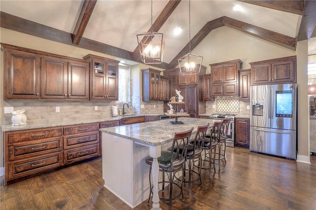 kitchen featuring a kitchen island, decorative light fixtures, sink, light stone counters, and stainless steel appliances