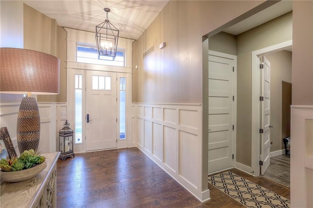 foyer entrance with an inviting chandelier and dark wood-type flooring