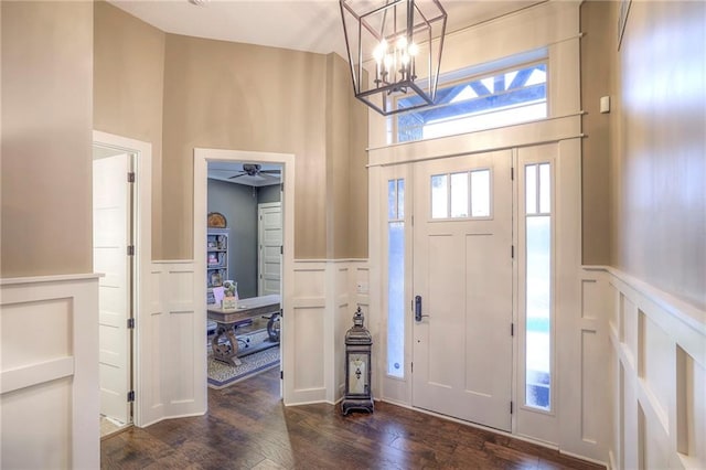 foyer entrance featuring an inviting chandelier, dark hardwood / wood-style flooring, and a high ceiling