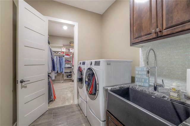 clothes washing area featuring separate washer and dryer, sink, and cabinets