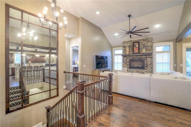 living room with high vaulted ceiling, ceiling fan with notable chandelier, hardwood / wood-style floors, and a fireplace