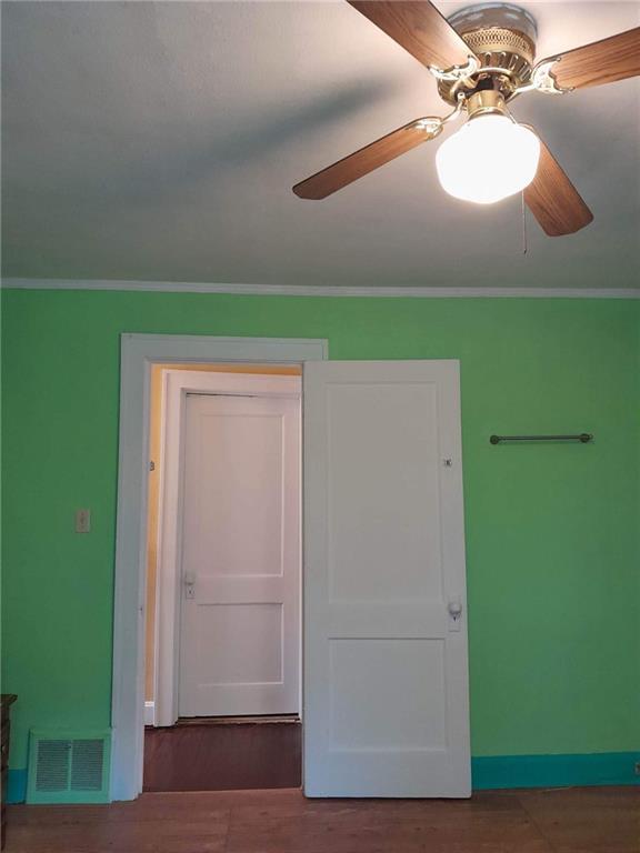 unfurnished room featuring ceiling fan, crown molding, and dark hardwood / wood-style floors