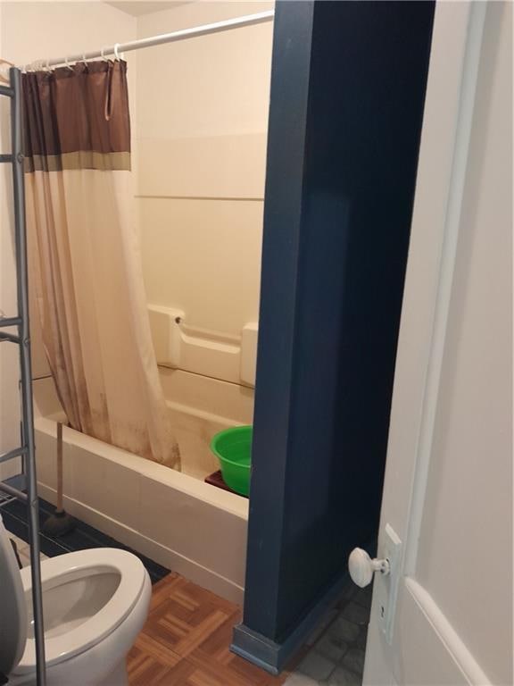 bathroom with toilet, shower / bath combo, and parquet floors