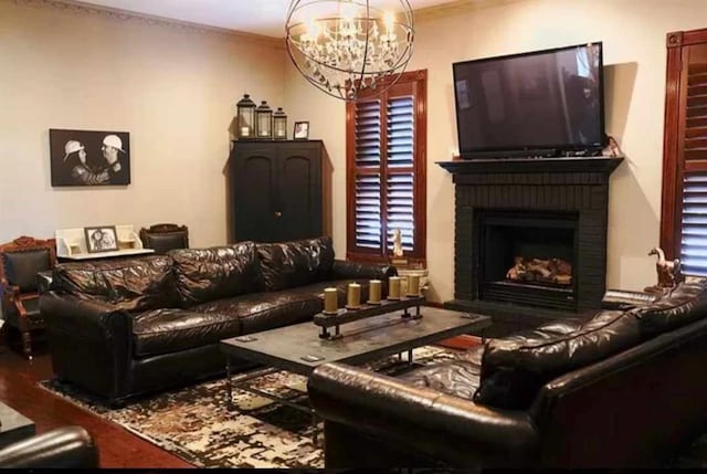 living room featuring crown molding, a notable chandelier, and a fireplace