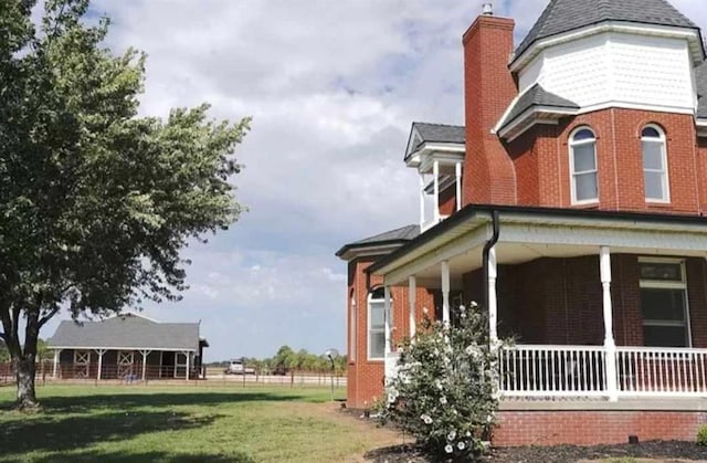 view of side of home featuring a lawn and covered porch