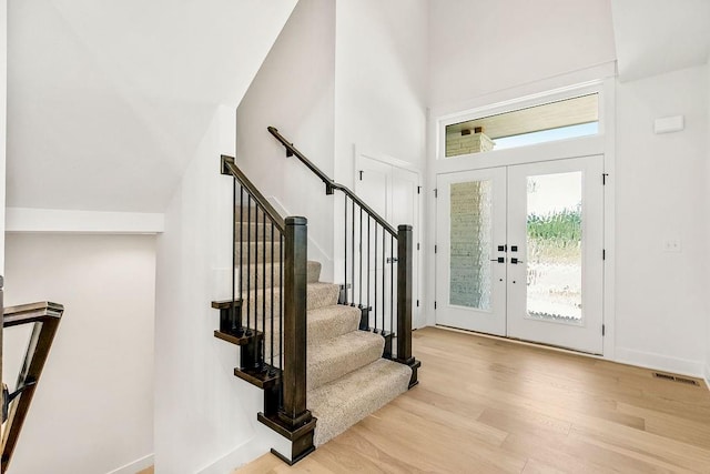 entrance foyer with a high ceiling, light hardwood / wood-style floors, and french doors