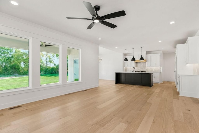 unfurnished living room with light wood-type flooring, ceiling fan, and sink