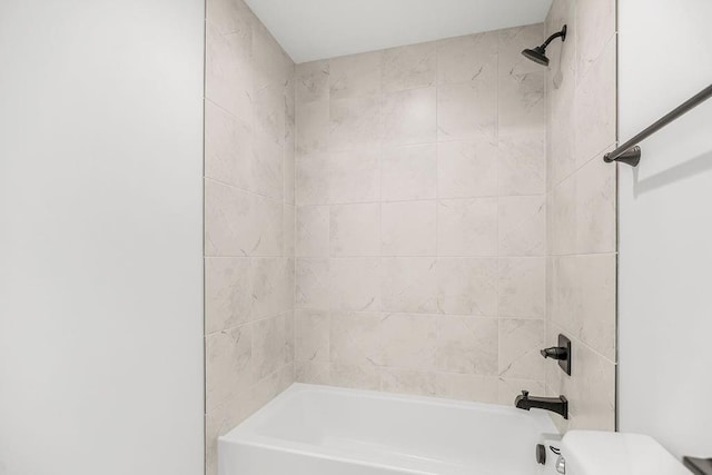 bathroom with tiled shower / bath combo and toilet