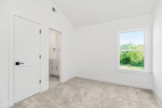 carpeted spare room with vaulted ceiling