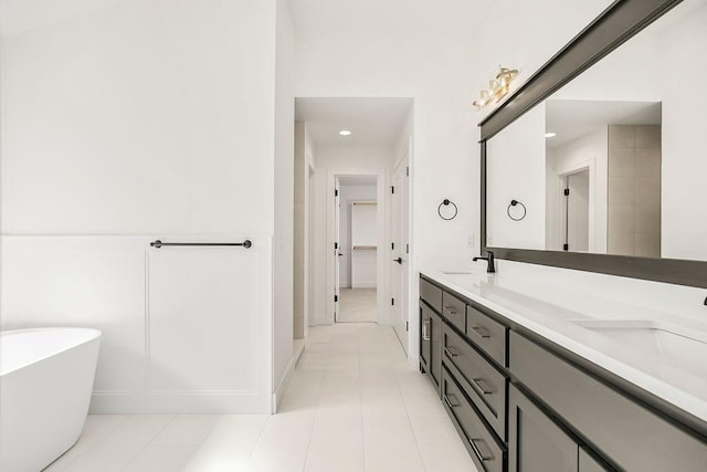 bathroom with a tub to relax in, vanity, and tile patterned floors