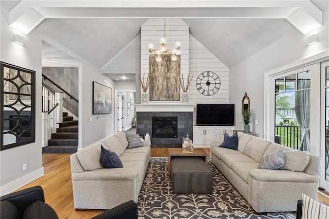 living room featuring high vaulted ceiling, wood-type flooring, an inviting chandelier, and a tile fireplace